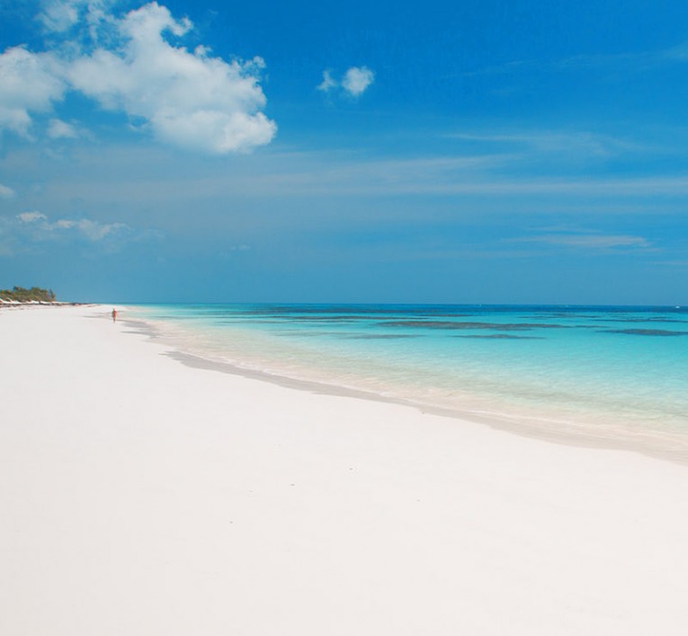White sand beach with clear blue water and clouds