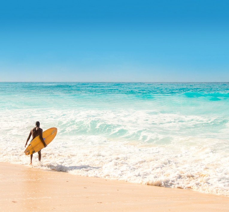 man holding surfboard while walking into the ocean